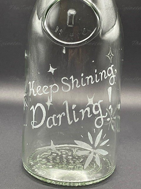 Close up view of front design with hand etched lettering on glass pitcher. Reads "Keep shining, Darling." Stars of various shapes and sizes surround the lettering.