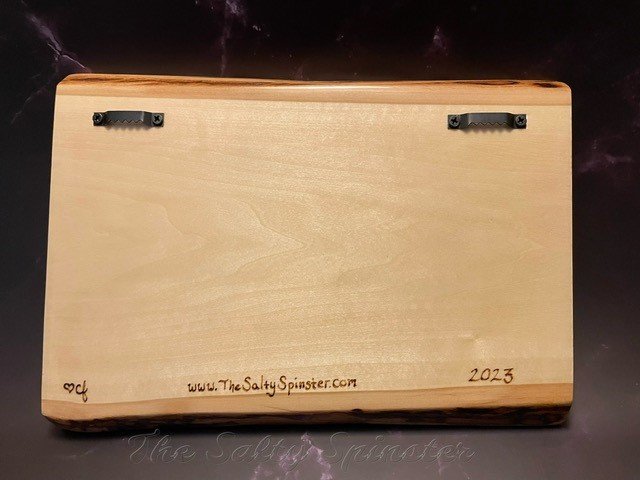 Backside of wood wall plaque showing two sawtooth hangers and artist's signature, website and date. 
